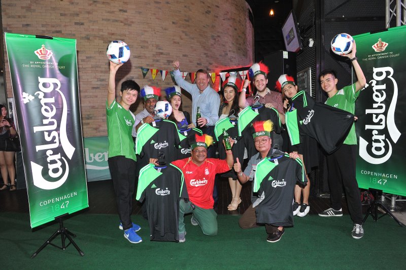 Seven guests posing for winning personalised jerseys from Carlsberg's juggling football challenge at the launch event of Play on Pitch campaign